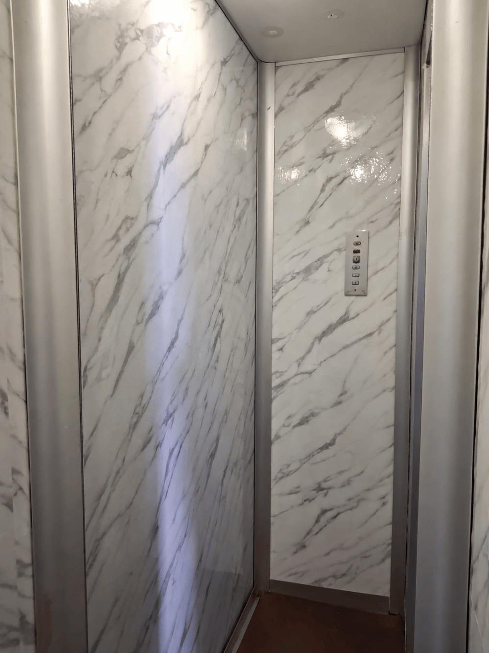 Rivestimento interno di un ascensore con grafica effetto marmo.